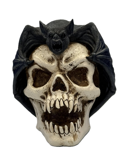 Front view of gothic bat perched on skull statue with wings spread and distressed bone detailing
