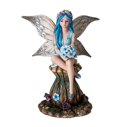 Front view of blue fairy sitting on mushroom holding flowers with detailed wings
