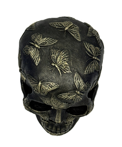 Top view of skull sculpture showing dense butterfly designs across the crown and upper surface
