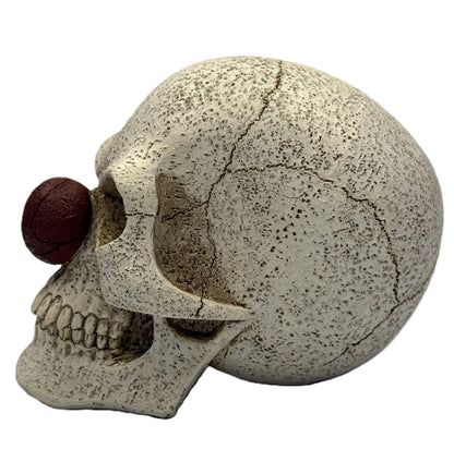 Left side view of clown skull figurine showing red nose cracked skull surface and realistic bone texture
