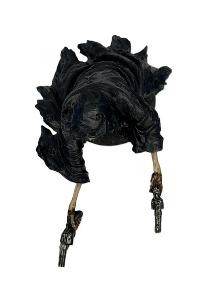 Top view of grim reaper statue emphasizing hooded cloak shape and extended skeletal arms holding revolvers
