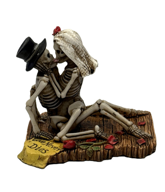 Front view of gothic skeleton couple statue kissing on wooden base with roses and love never dies plaque
