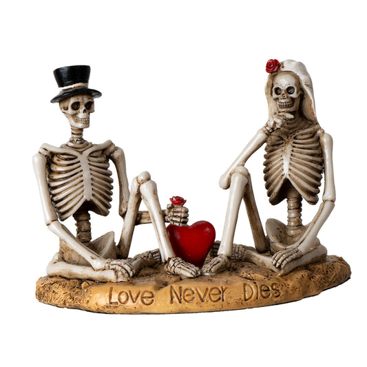 Front view of skeleton couple statue with red heart and love never dies engraving
