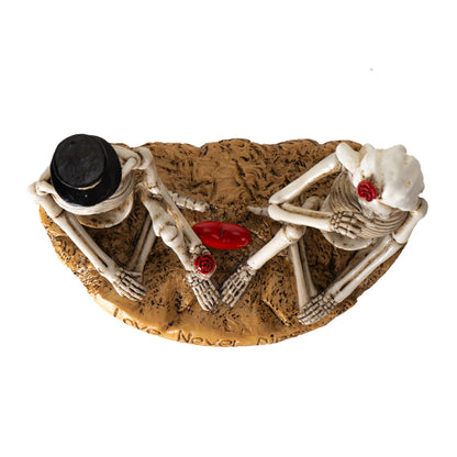 Top view of gothic skeleton couple with heart and rose detail between them
