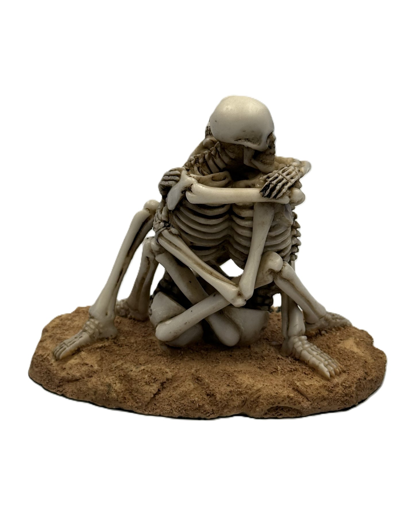Side view of embracing skeleton lovers statue highlighting intertwined arms and legs
