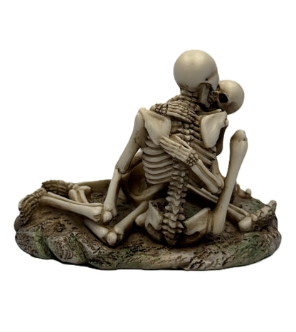 Back view of skeleton couple statue showing detailed spine and embrace posture on textured base
