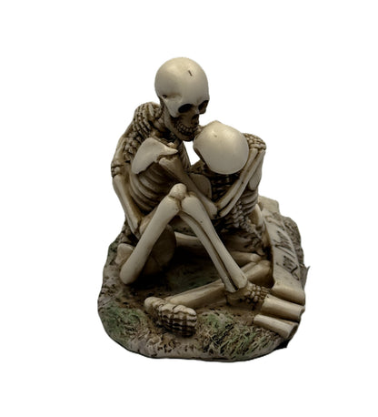 Side view of gothic skeleton lovers figurine highlighting seated pose and intertwined arms

