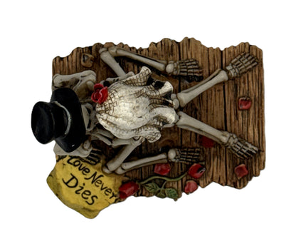 Top view of skeleton couple figurine with veil rose detail and wooden base engraved love never dies
