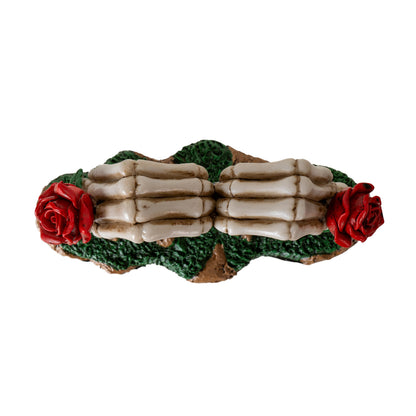 Top view of skeleton hands forming heart shape with red roses on each side
