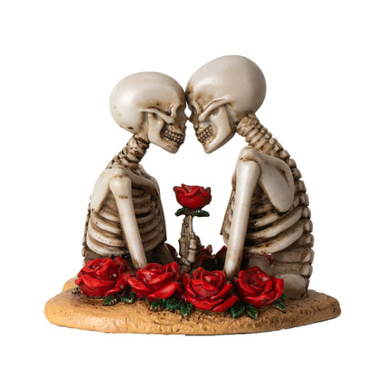 Side view of gothic skeleton couple leaning together surrounded by red roses
