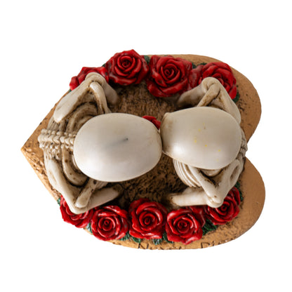 Top view of skeleton lovers figurine showing heads touching and rose arrangement
