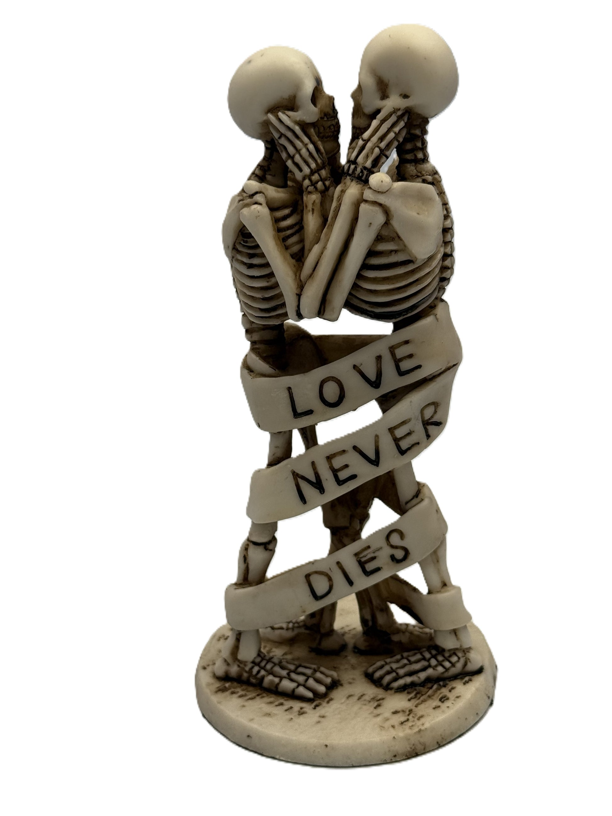 Front view of gothic skeleton couple statue standing and embracing with “Love Never Dies” ribbon wrapped around bodies
