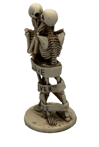 Side view of skeleton couple embracing decor with wrapped “Love Never Dies” ribbon and detailed resin finish
