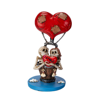 Front view of skeleton couple holding heart with stitched balloon above them
