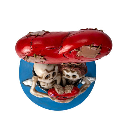 Top view of stitched heart balloon above skeleton couple figurine
