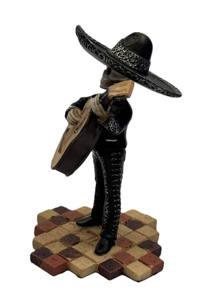 Side view of skeleton mariachi bass guitarist figurine with detailed black outfit and sombrero resin statue
