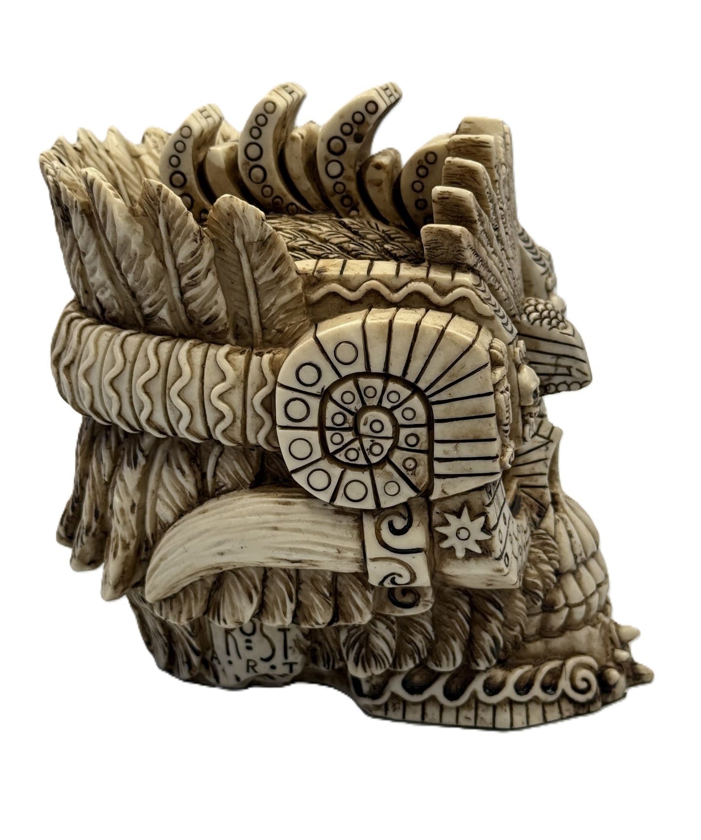 Side detail view of Aztec skull statue showing spiral carvings and ornamental tribal motifs
