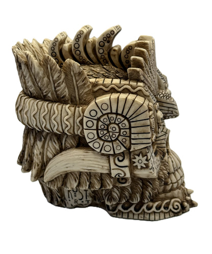 Side detail view of Aztec skull statue showing spiral carvings and ornamental tribal motifs
