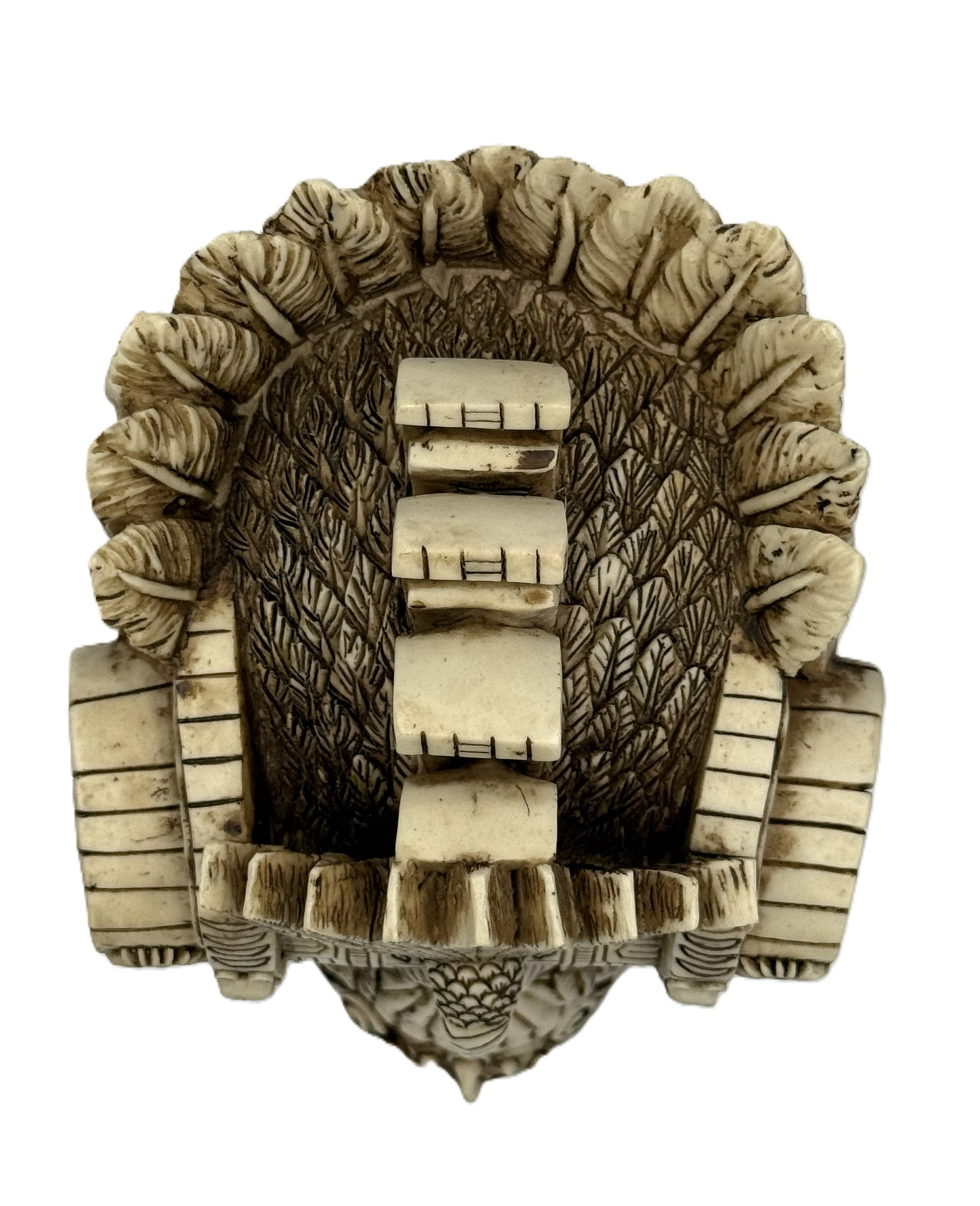 Top view of Aztec skull statue displaying detailed feather pattern and sculpted crown centerpiece
