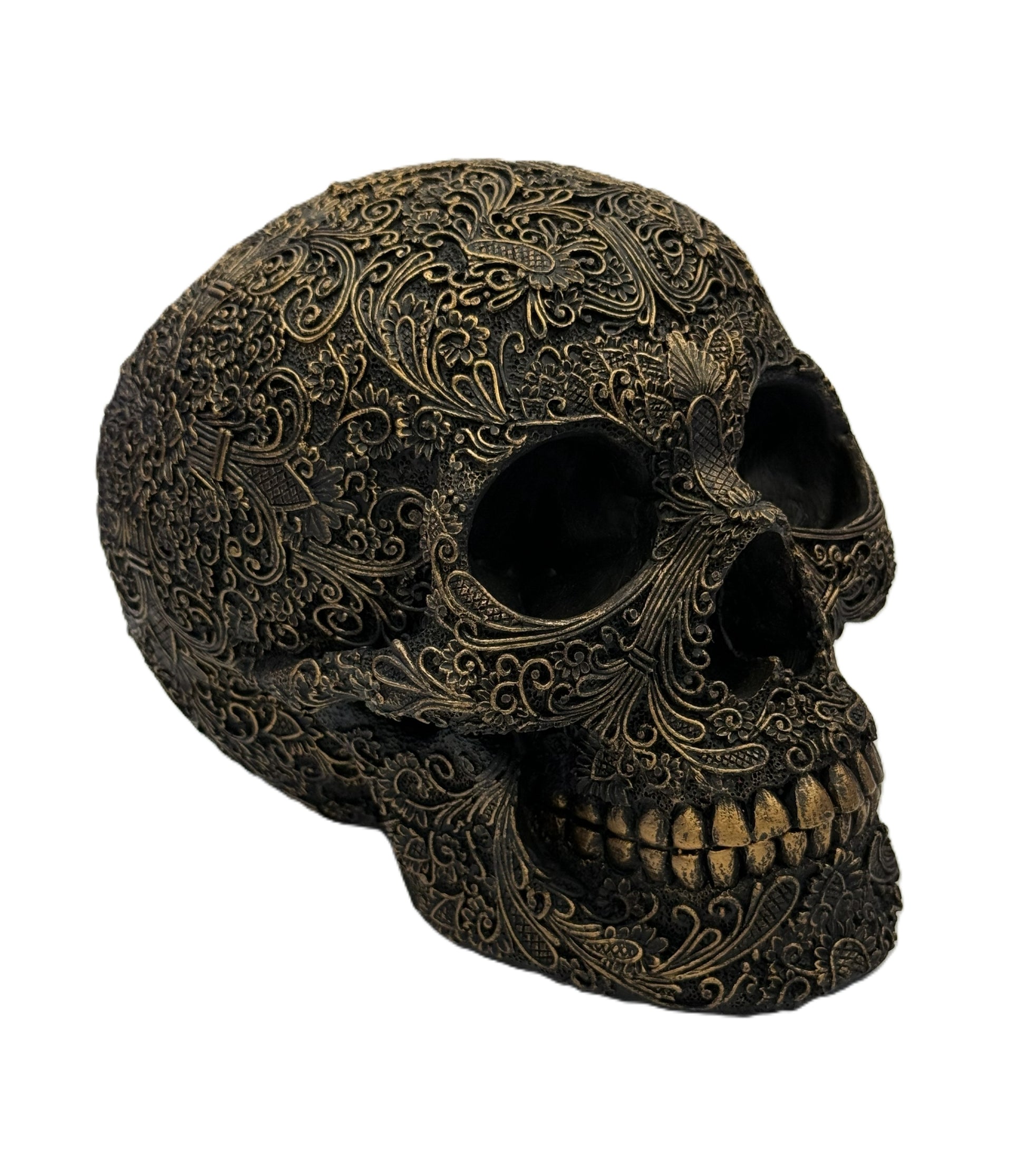 Front right angled view of carved skull showing deep eye sockets and intricate filigree details
