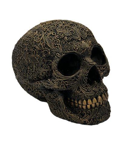 Front right angled view of carved skull showing deep eye sockets and intricate filigree details
