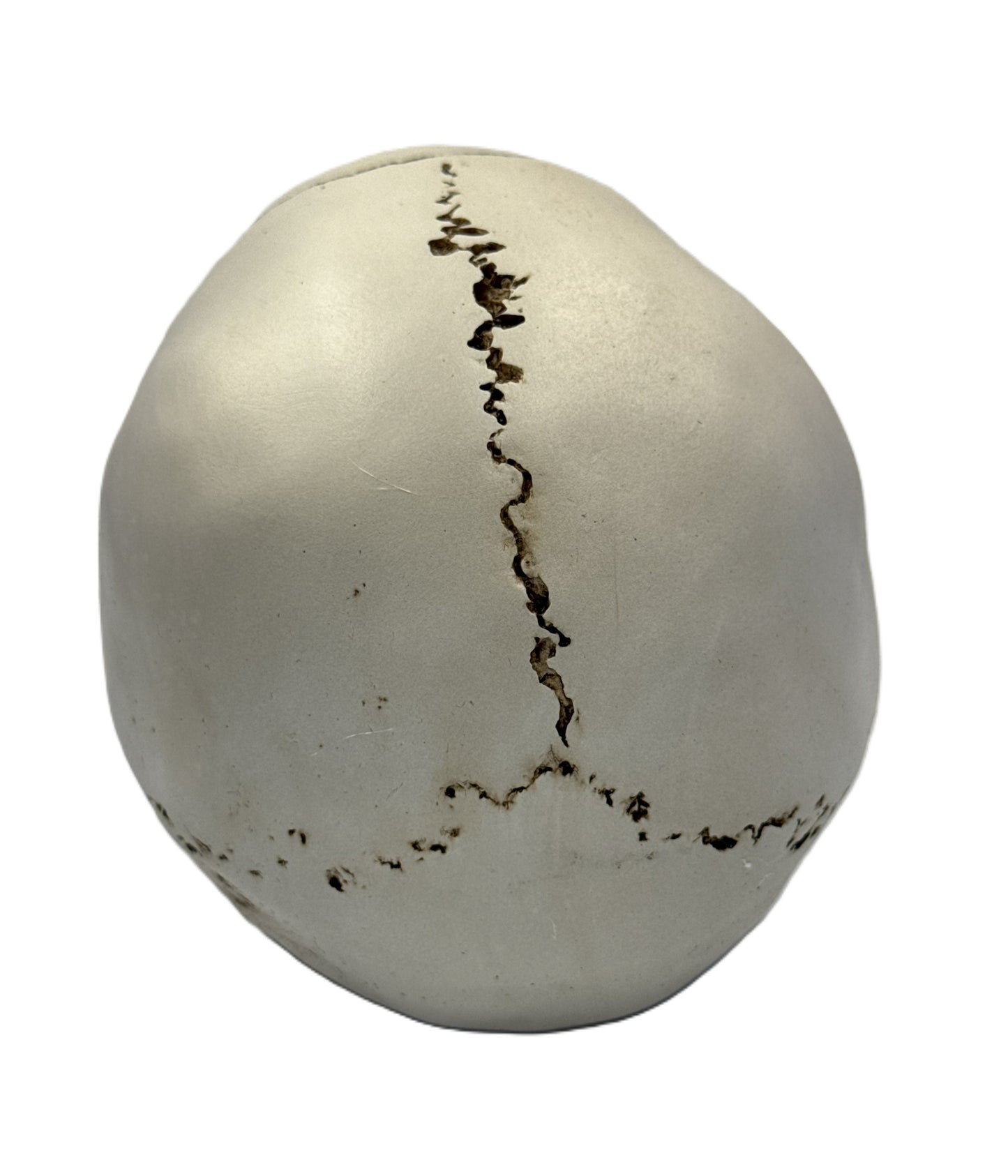 Top view of aged skull sculpture highlighting prominent crack running across the crown
