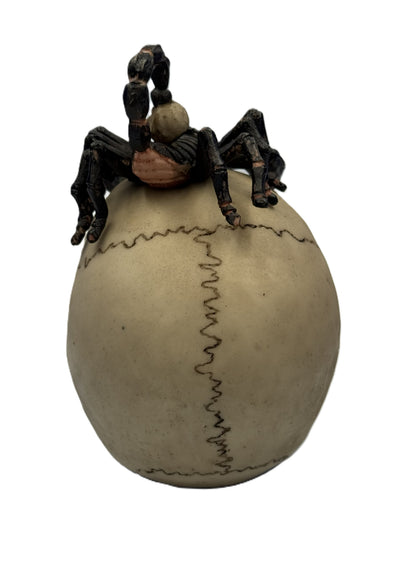 Back view of skull figurine showing scorpion tail and cracked bone texture details

