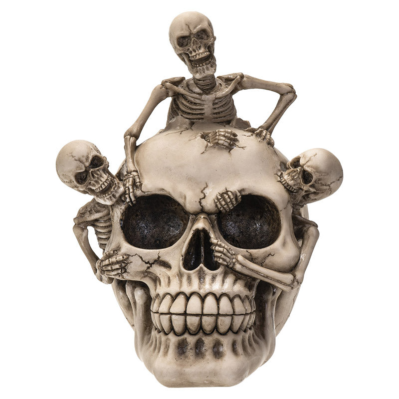 Front view of skull with three skeletons climbing over detailed cracked surface
