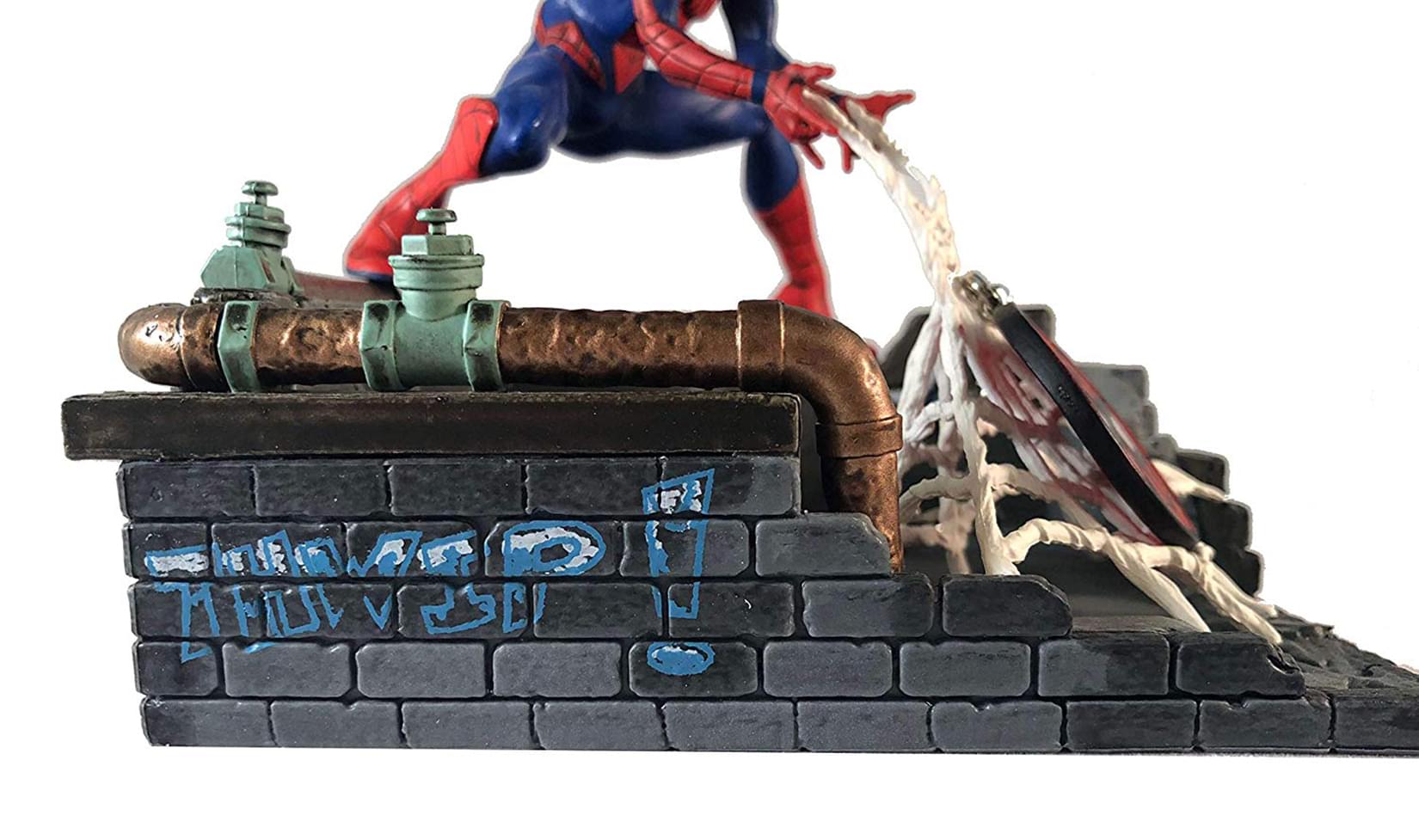 close-up of Spider-Man statue rooftop base with graffiti and pipe details
