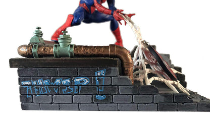 close-up of Spider-Man statue rooftop base with graffiti and pipe details
