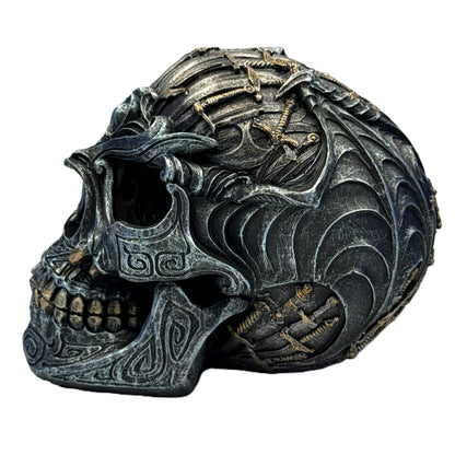 Left side view of skull statue with embedded swords and detailed gothic engravings
