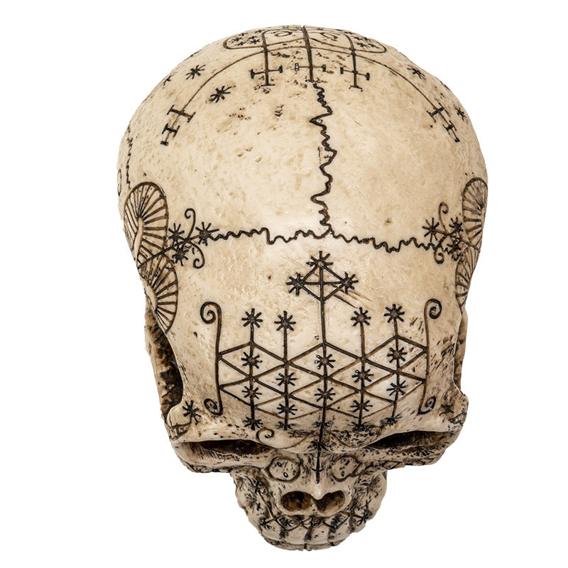 Back view of voodoo skull statue showing detailed ritual symbols and geometric engravings
